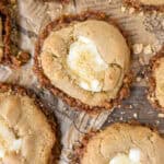 overhead photo of cheesecake cookies on brown newsprint paper with graham cracker crumbles.