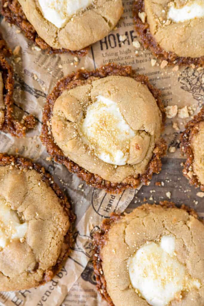 overhead photo of cheesecake cookies on brown newsprint paper with graham cracker crumbles.
