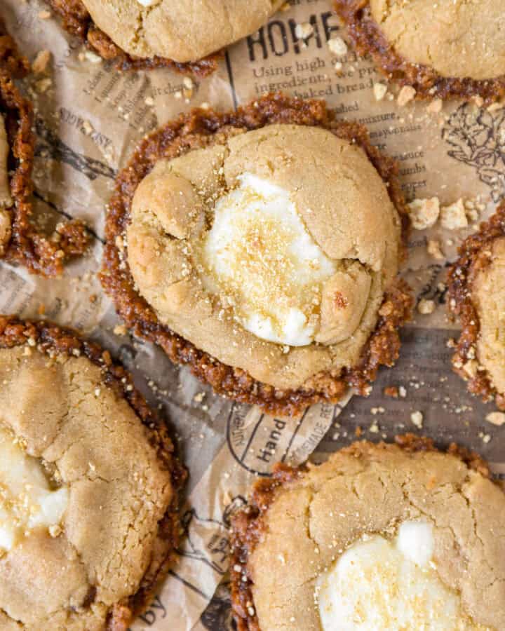 overhead photo of cheesecake cookies on brown newsprint paper with graham cracker crumbles.