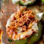 fork scooping the sausage orzo filling from a green bell pepper stuffed pepper.