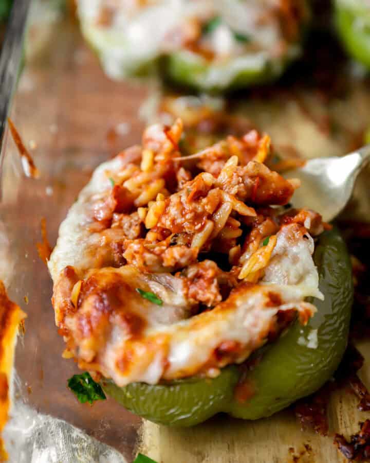 fork scooping the sausage orzo filling from a green bell pepper stuffed pepper.