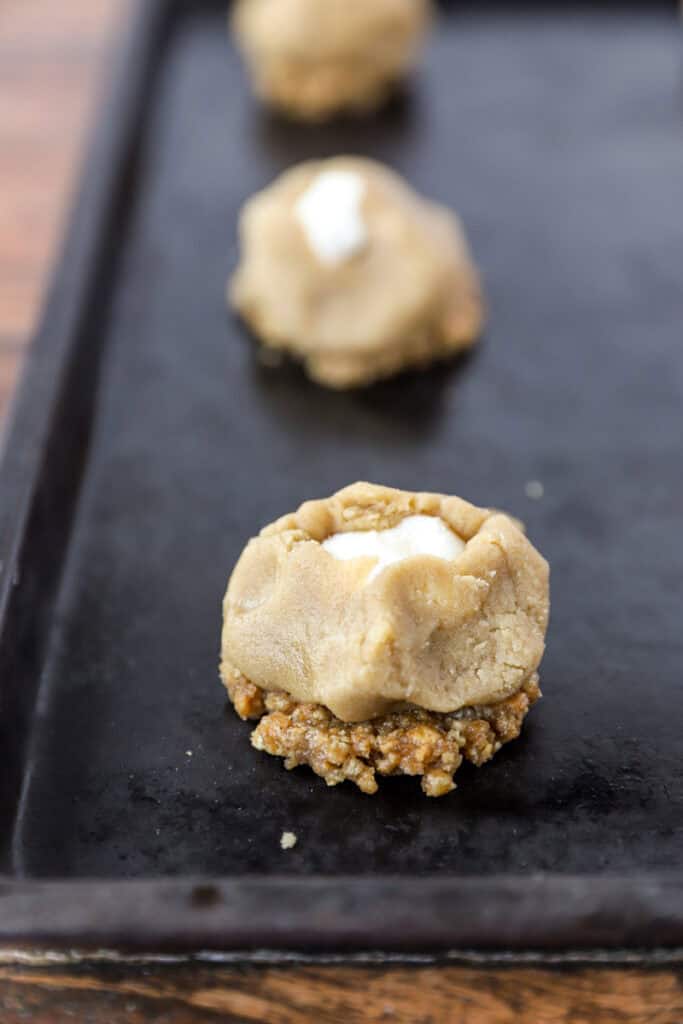 unbaked cheesecake cookies on dark nonstick baking sheet.