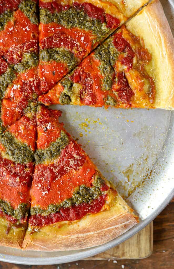overhead photo of the baked pizza on a stainless steel pizza pan with one slice missing.