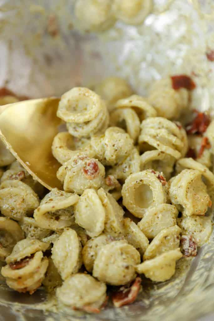 side by side 2 photos. Left shows overhead view of pesto sauce in a pot. Left shows the orecchiette and bacon mixed in.