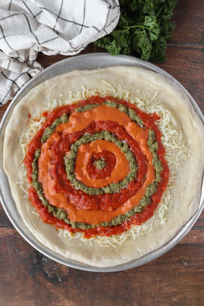 overhead photo of the pizza now swirled with all 3 sauces: marinara, vodka, pesto.