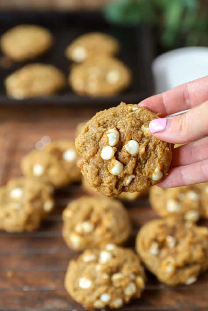 a hand holding one of the cookies. The remaining cookies on the cooling rack blurred in the background.