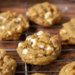 pumpkin white chocolate chip cookies in a wire cooling rack on a wood surface.