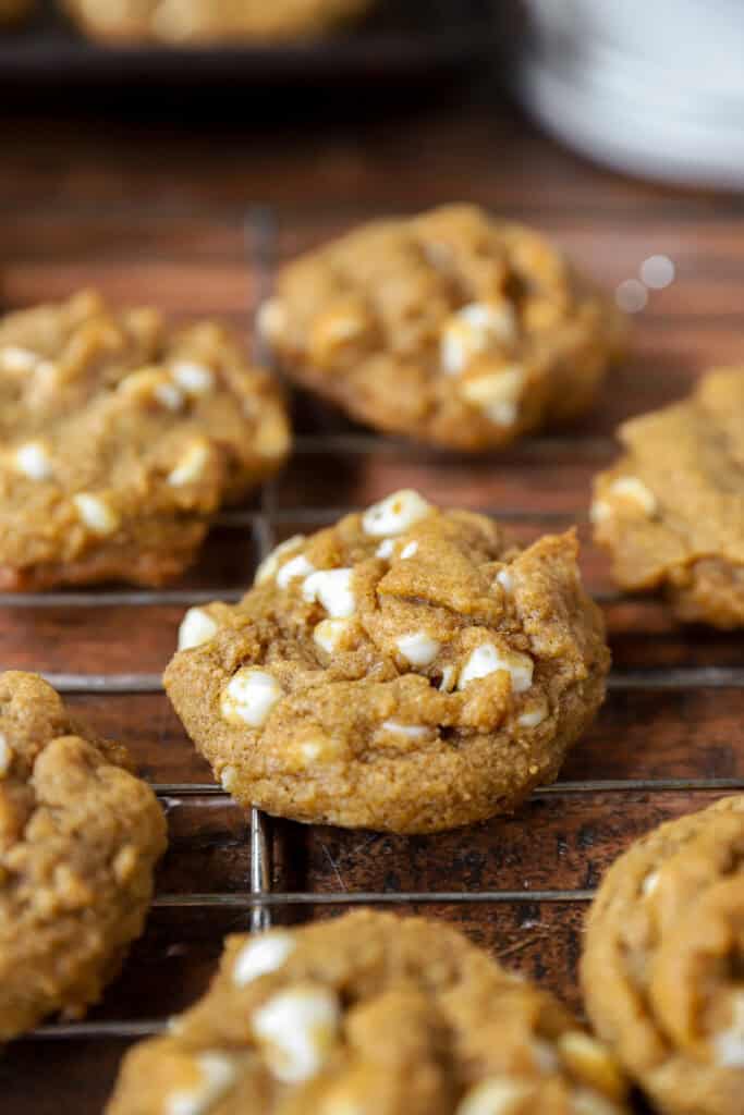 pumpkin white chocolate chip cookies in a wire cooling rack on a wood surface.