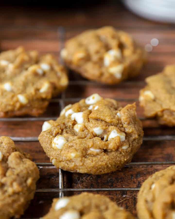 pumpkin white chocolate chip cookies in a wire cooling rack on a wood surface.