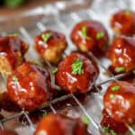 BBQ Chicken meatballs with parsley on a cooling rack on a foil lined baking sheet.