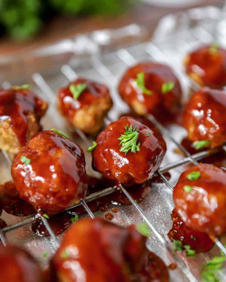 BBQ Chicken meatballs with parsley on a cooling rack on a foil lined baking sheet.