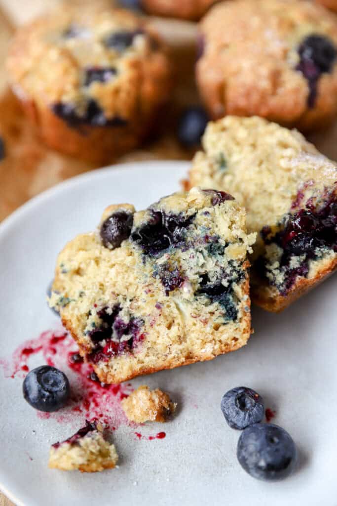 one of the muffins cut open to show the interior texture on a round grey plate.