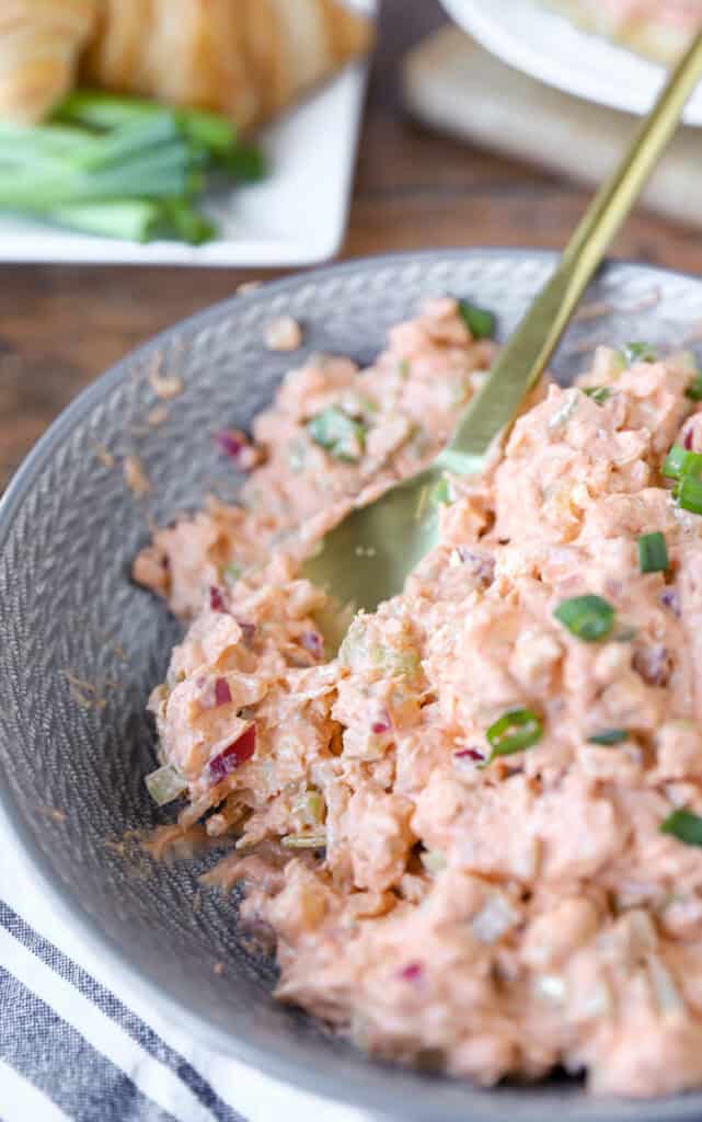the mixed Buffalo chicken chicken salad in a round grey bowl with a gold serving spoon.