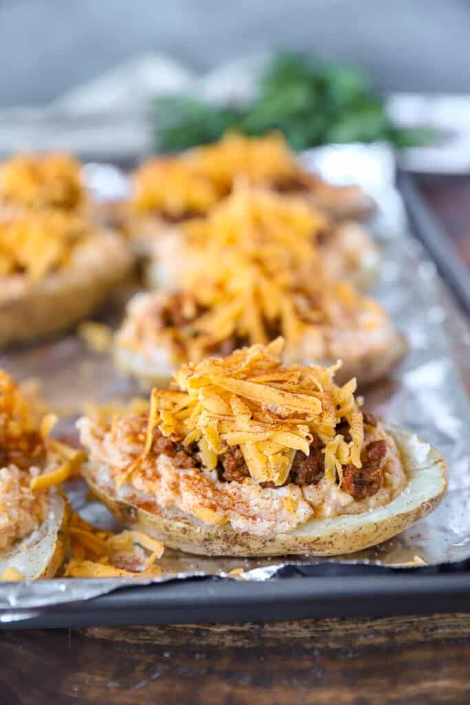 The potatoes now topped with the shredded Cheddar cheese on a foil lined baking sheet.