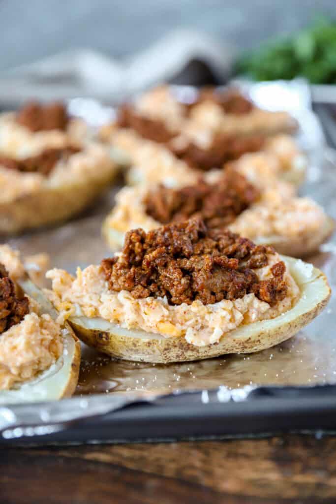 The potatoes now filled with the taco meet on a foil lined baking sheet.