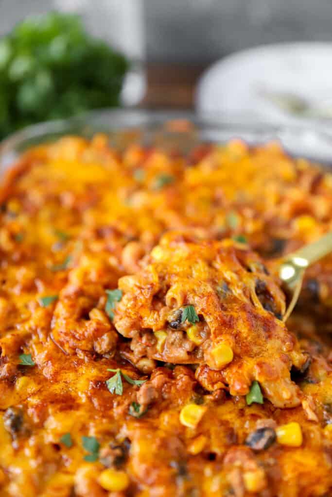 a gold serving spoon scooping from the taco pasta bake.