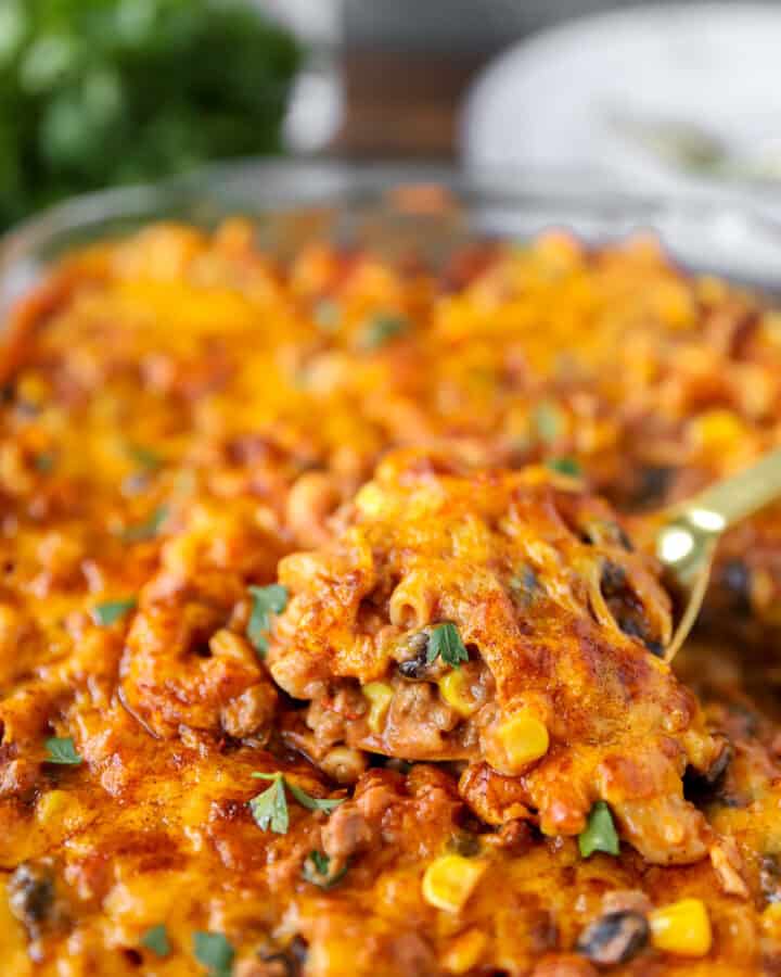 a gold serving spoon scooping from the taco pasta bake.