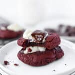 stack of 2 red velvet cookies on round white plates.