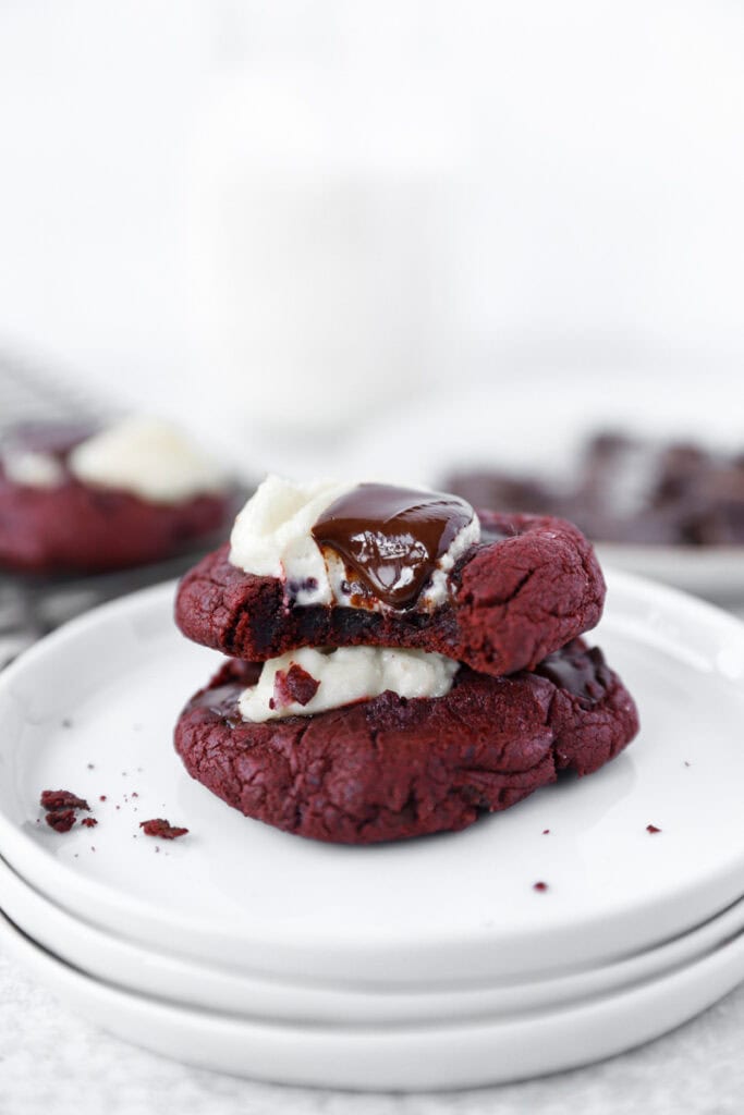 stack of 2 red velvet cookies on round white plates.