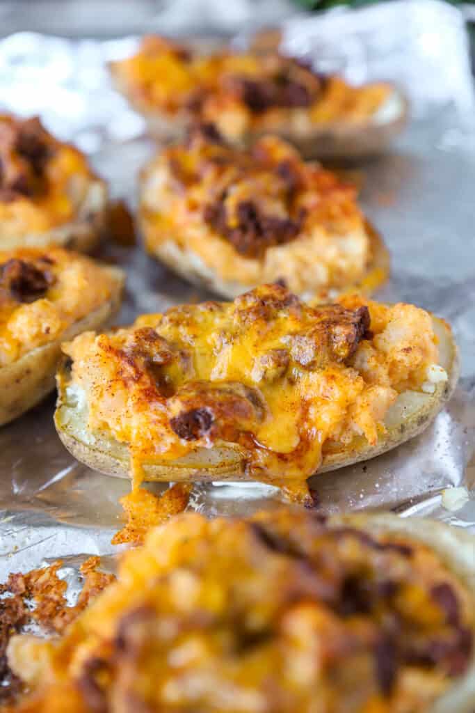 the twice baked potatoes fresh from the oven with melty Cheddar cheese on a foil lined baking sheet.
