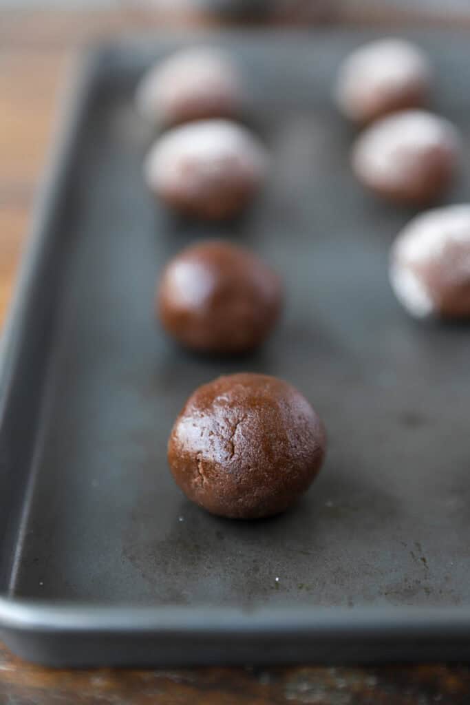 rolled cookie dough balls on a baking sheet.
