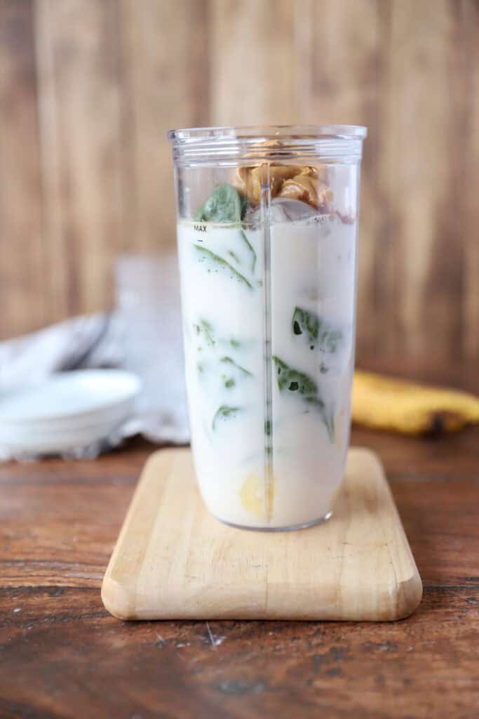 all ingredients unblended in the Magic Bullet cup on a wood cutting board.