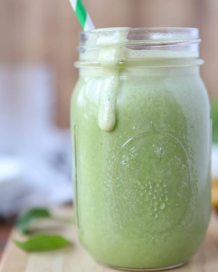 banana spinach smooth in a mason jar glass with a green and white striped straw.