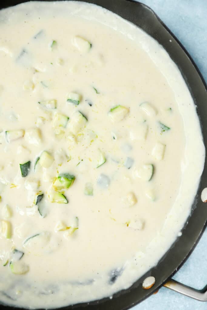 overhead photo of the lemon cream sauce with zucchini mixed in in a nonstick pan.