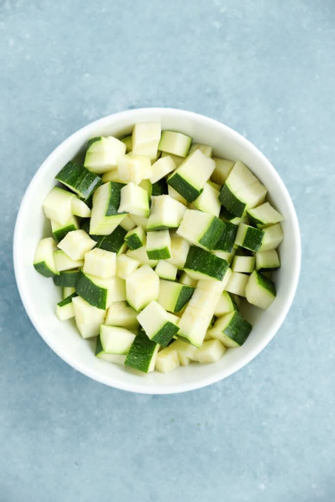 overhead photo of diced zucchini in a white bowl.