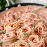 spiraled linguini noodles in bacon tomato sauce pasta in a nonstick pan.