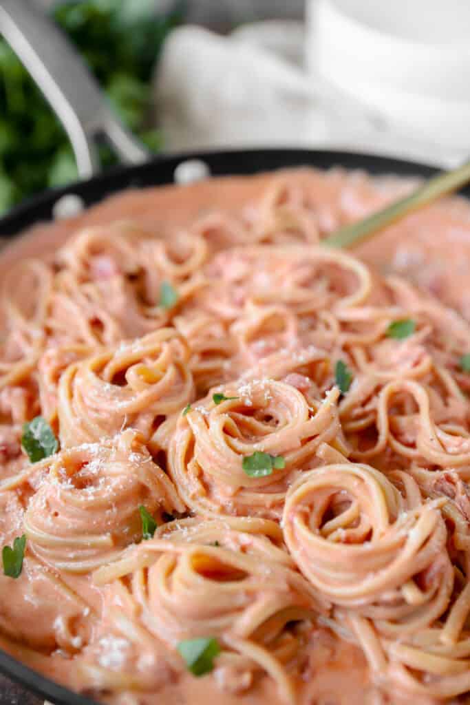 spiraled linguini noodles in bacon tomato sauce pasta in a nonstick pan.