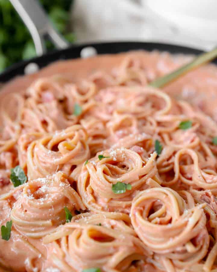 spiraled linguini noodles in bacon tomato sauce pasta in a nonstick pan.