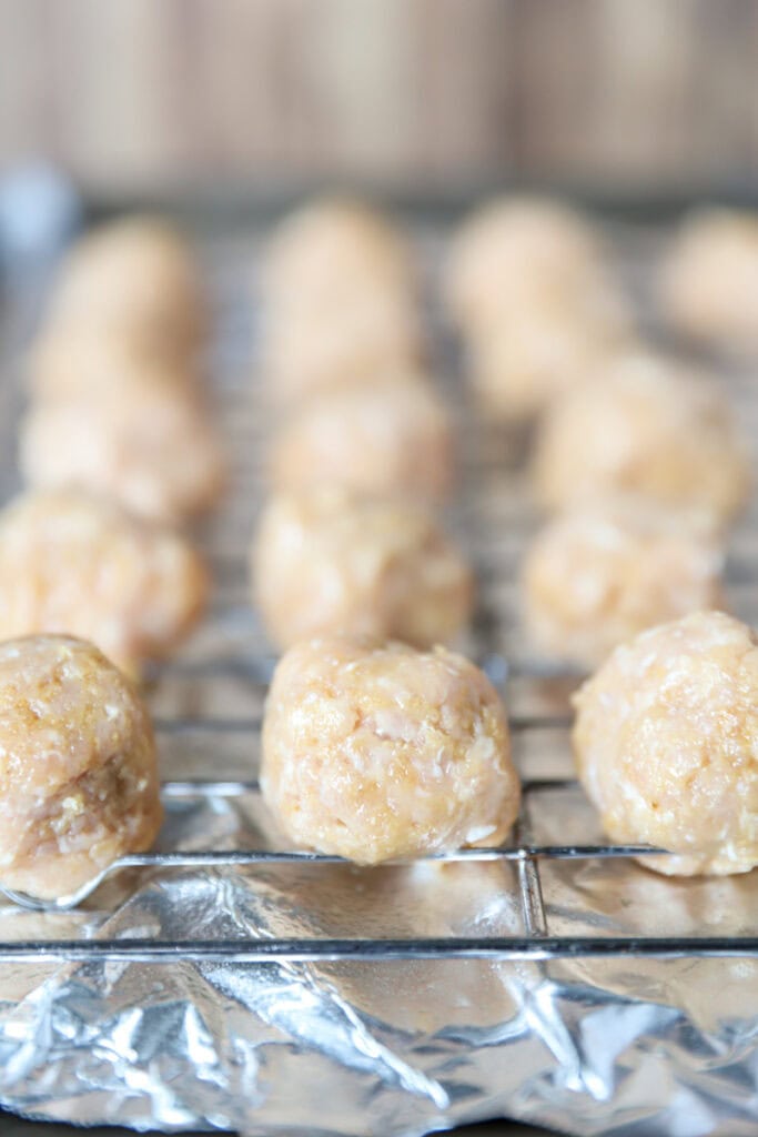 the formed meatballs on a baking rack on a foil-lined baking sheet.