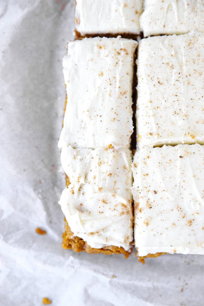 overhead photo of the iced pumpkin cookie bars on parchment paper.