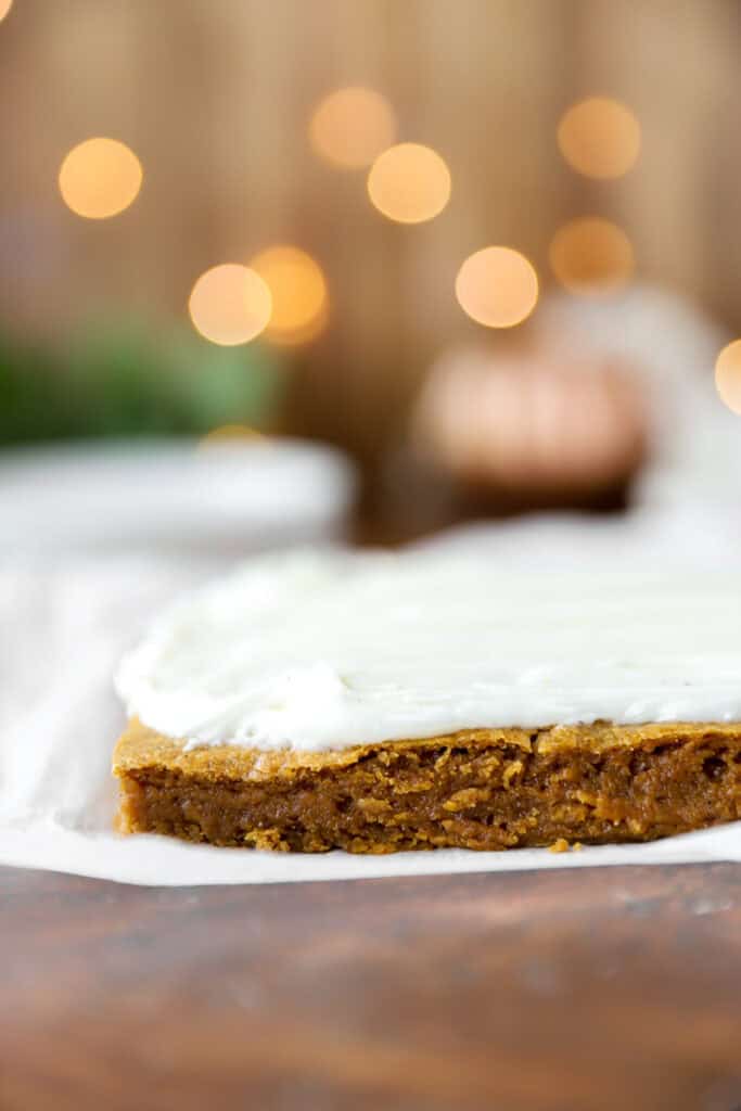 iced pumpkin cookie bars on parchment paper on a wood surface.