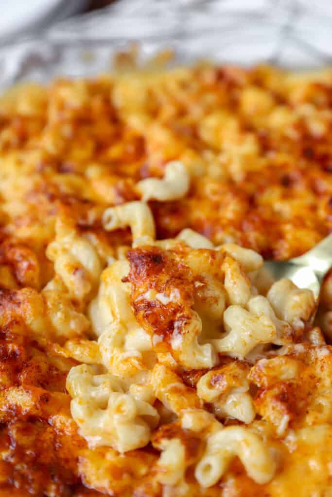a large spoon scooping the mac and cheese from the baked casserole.