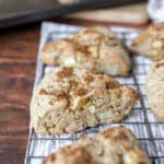 apple cinnamon scones on a baking rack on a wood surface.