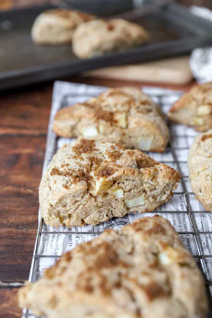 apple cinnamon scones on a baking rack on a wood surface.