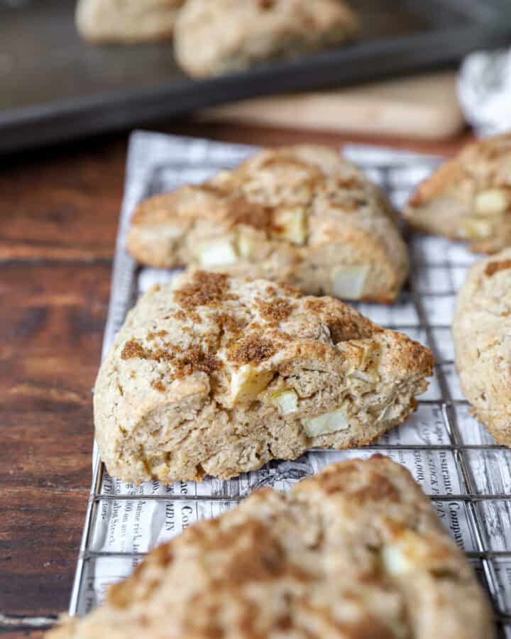 apple cinnamon scones on a baking rack on a wood surface.