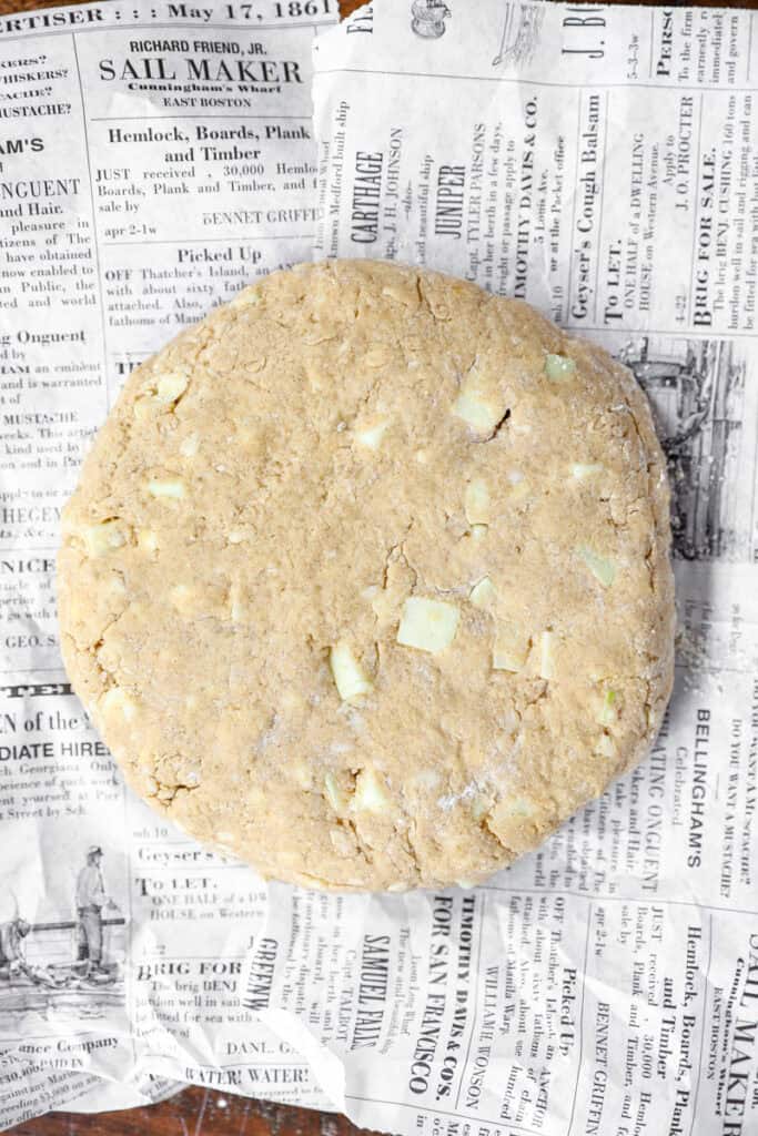overhead photo of the dough molded into a 7" circle on newsprint paper.