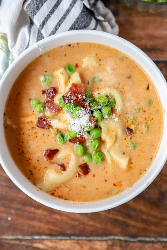 overhead photo of tortellini soup in a round white bowl.