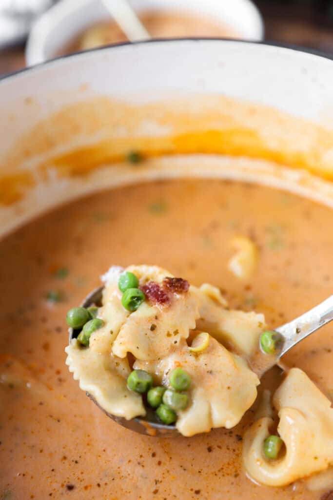 a ladle spooning the tortellini bacon and pea soup from the rest of the soup below it.