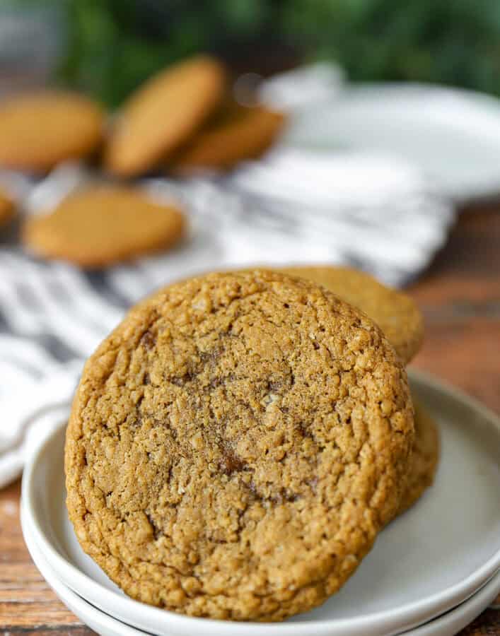a stack of the oatmeal cookies with one positioned closer to the camera on a stack of 2 round white plates.